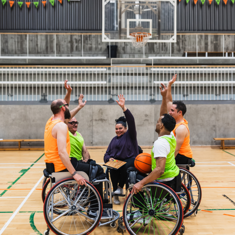 Creating inclusive opportunities through adaptive sport Wheelchair basketball players celebrating together, promoting inclusive sport, teamwork and belonging.